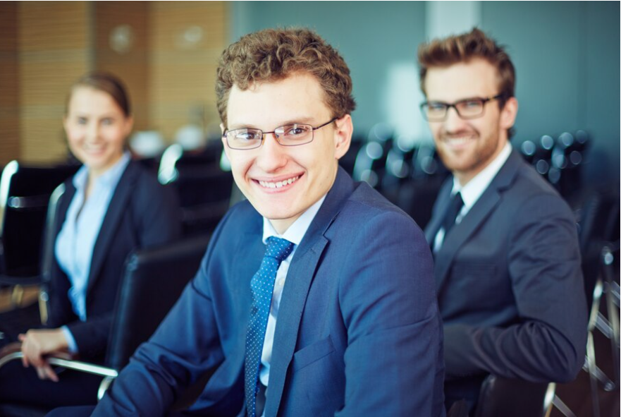 A pic of three Caucasian male professionals looking smart in blue formals, smiling at the camera